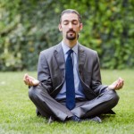 young businessman meditating in the garden